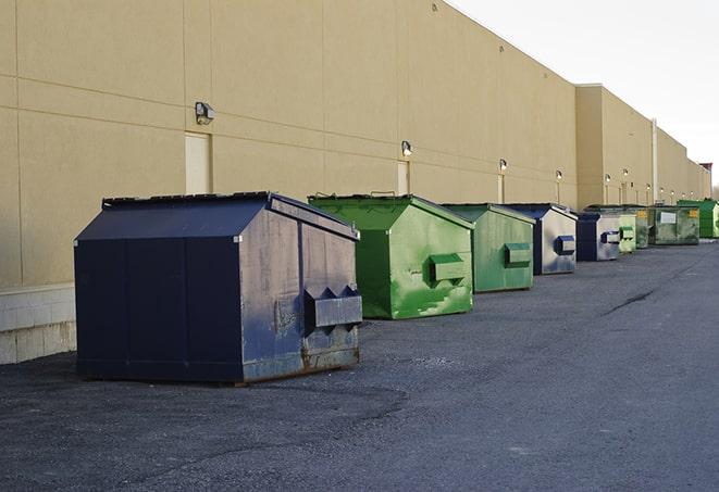 a construction worker unloading debris into a blue dumpster in Birdsboro